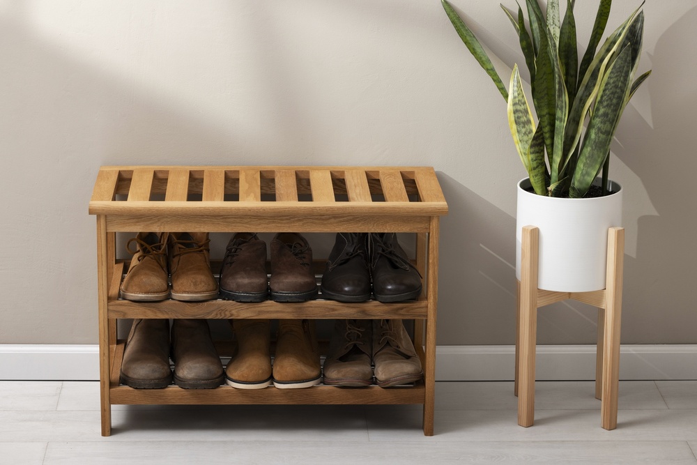 Un zapatero de madera de diseño práctico y estético, colocado en el recibidor junto a una planta decorativa. Esta combinación no solo mantiene el orden, sino que aporta calidez y estilo al primer espacio que se ve al entrar en casa.